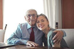 An elderly client and a young Care Giver smile together, embracing in a warm moment.
