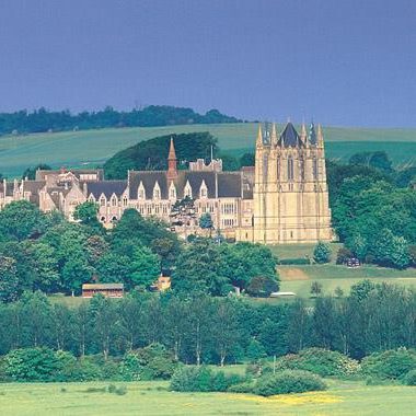 Lancing College Lancing College with towering spires, surrounded by lush greenery and rolling hills.