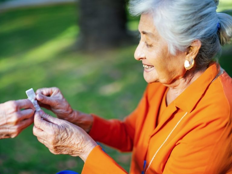 An elderly woman with a concerned expression surrounded by prescription medication bottles.